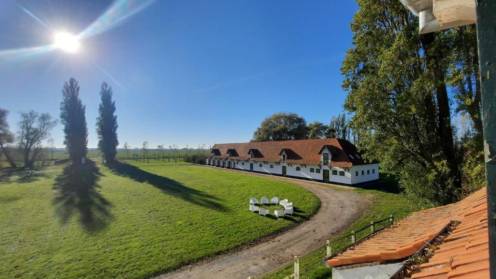 um grande edifício branco com um telhado vermelho num campo verde em La Compagnie des Moëres em Veurne