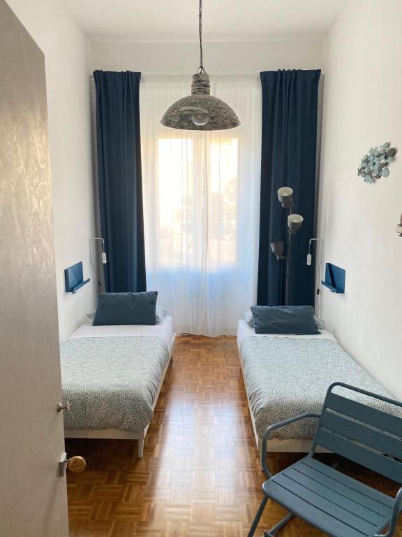 a room with two beds and a chair and a window at B&B Monteverdi L'Arancio in Florence