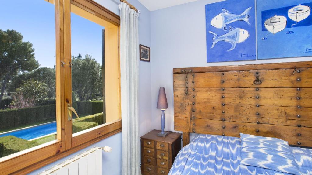 a bedroom with a wooden headboard and a window at 1Arca - Llafranc in Llafranc