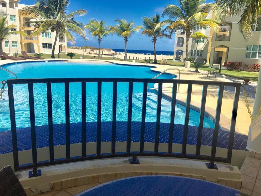 a view of a swimming pool from a balcony with palm trees at Haudimar PH Beachfront Apt 4BR/3Bath in Isabela