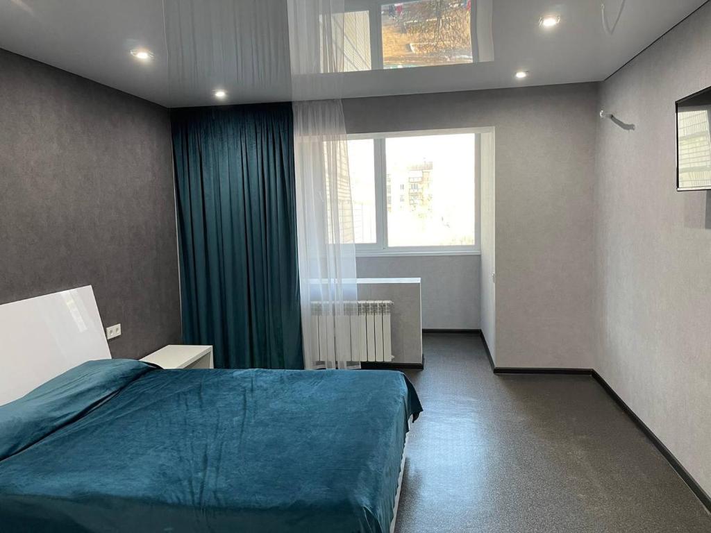 een slaapkamer met een blauw bed en een raam bij Люкс апартаменты, Кривой Рог, 5й Заречный, Покровский район in Krivoy Rog