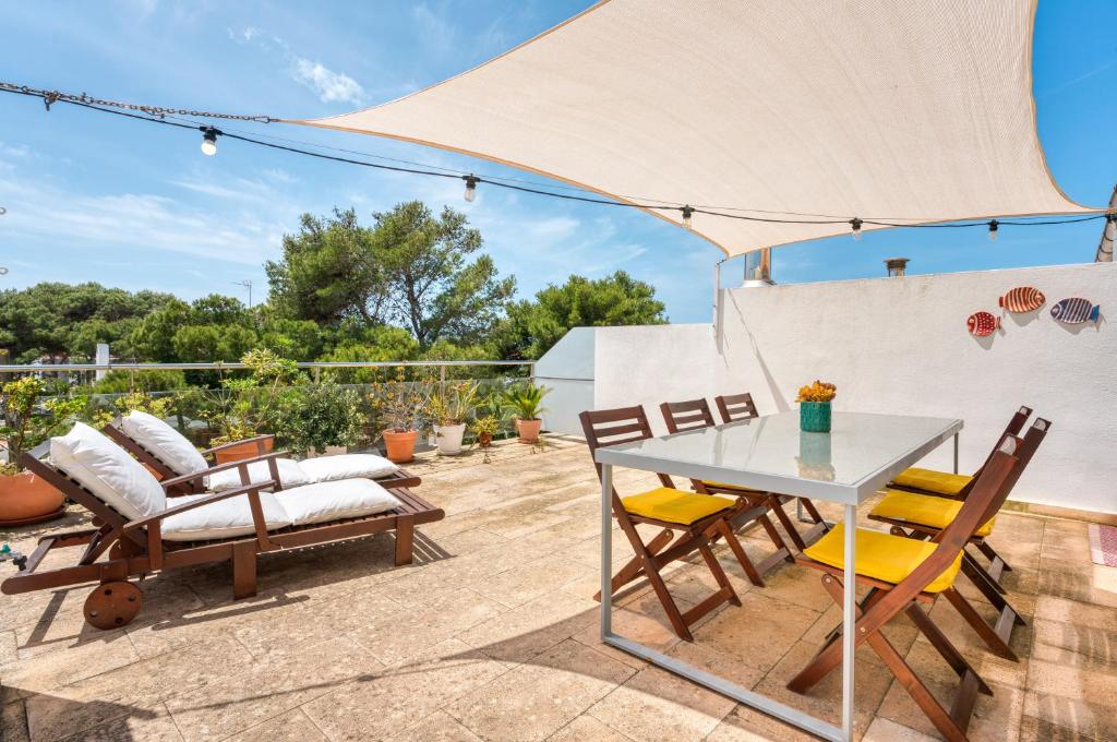 un patio con mesa y sillas en Ático Playa Santandria con Piscina y Wifi en Ciutadella