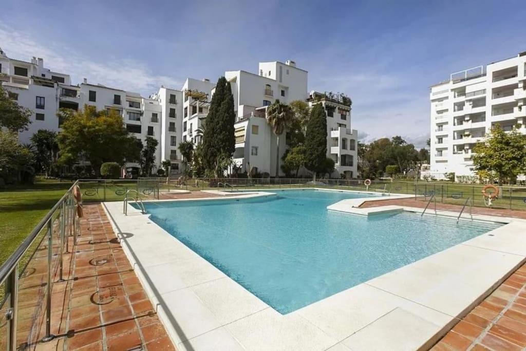 a large swimming pool in front of some buildings at Caprichoso apartamento en el corazon de Puerto Banus in Marbella
