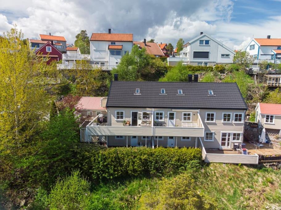 duży biały dom na wzgórzu z domami w obiekcie Sentralt rekkehus med solrik veranda! w mieście Arendal