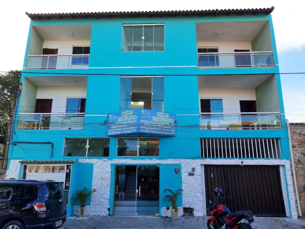 a blue building with a motorcycle parked in front of it at Suítes Xodo Tour in Arraial do Cabo