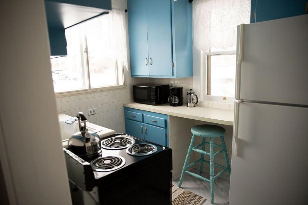 - une cuisine avec des placards bleus, une cuisinière et un tabouret dans l'établissement Charming French Studio Apartment, à Laramie