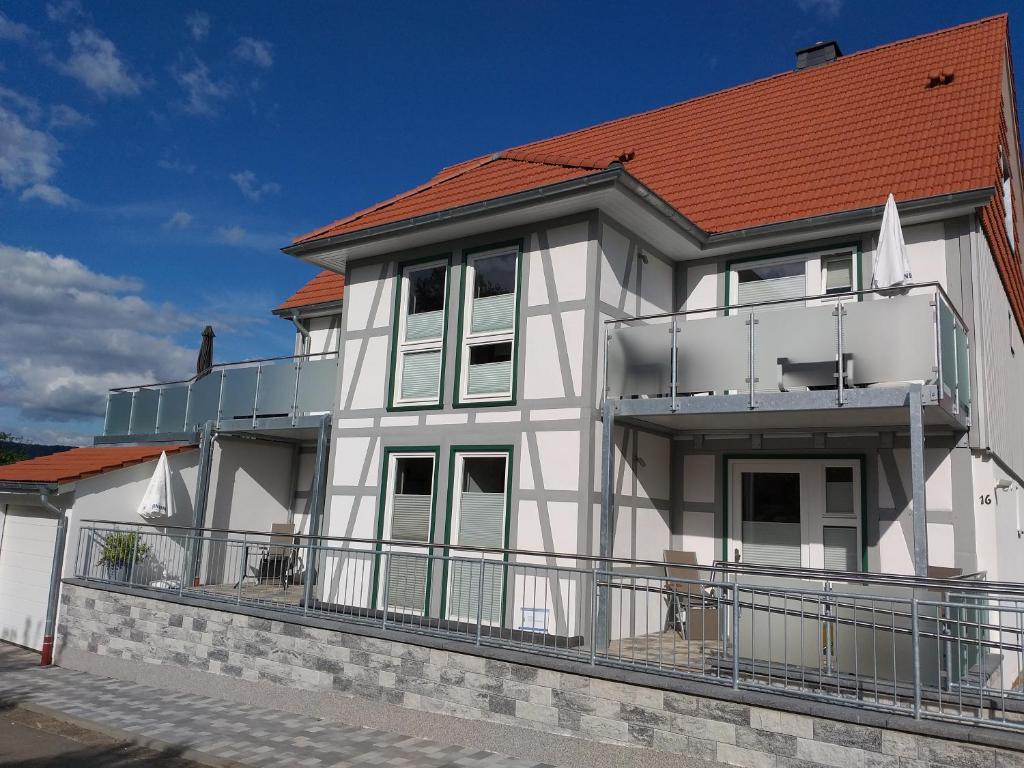 ein weißes Haus mit orangefarbenem Dach in der Unterkunft Ferienwohnungen Zum Lindenwirt in Weißehütte