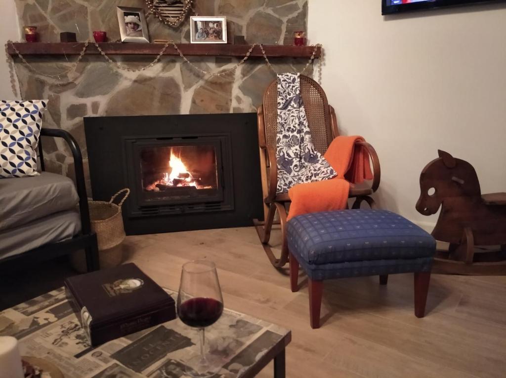ein Wohnzimmer mit einem Kamin und einem Glas Wein in der Unterkunft Casa Rural La ilusion in Málaga