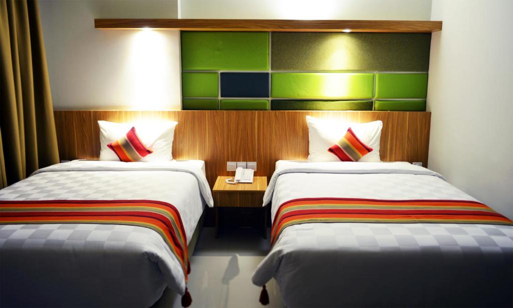 a hotel room with two beds and a table at Kyriad Hotel Airport Jakarta in Tangerang