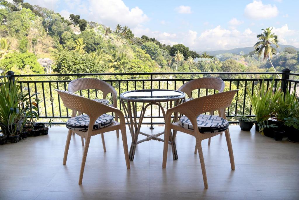 a table and chairs on a balcony with a view at Chathu Holiday Home in Kandy