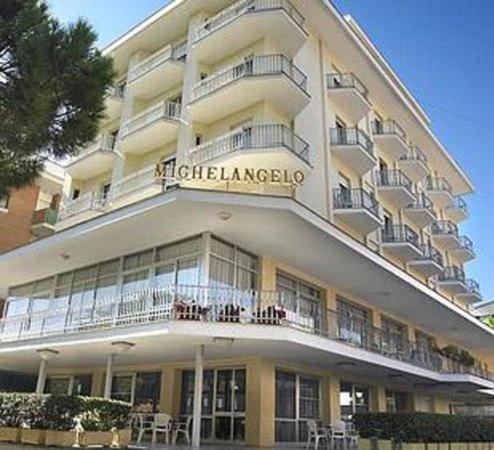 un gran edificio blanco con balcones, mesas y sillas en Hotel Michelangelo, en Bellaria-Igea Marina