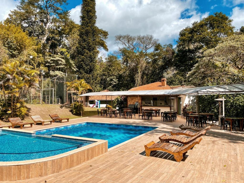 uma piscina com cadeiras e mesas e uma casa em Hotel Vila Bavária em Petrópolis