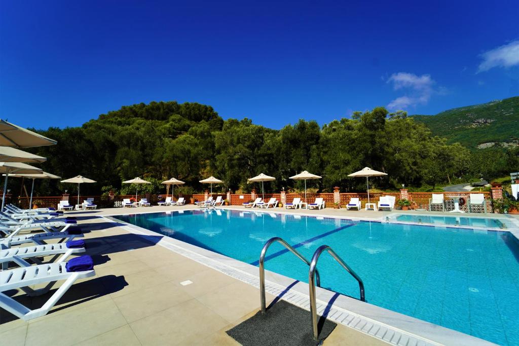 einen großen Pool mit Liegestühlen und Sonnenschirmen in der Unterkunft Angelika Elegant Hotel in Parga