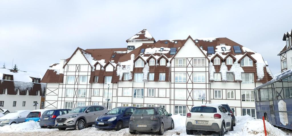 Un gran edificio con coches aparcados delante. en Gabi Apartments Kopaonik - Kraljevi cardaci, en Kopaonik
