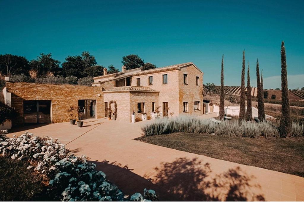 una gran casa de piedra con un patio y árboles en Villa Mozzafiato con Jacuzzi o Camino Toscana Montepulciano, en Valiano