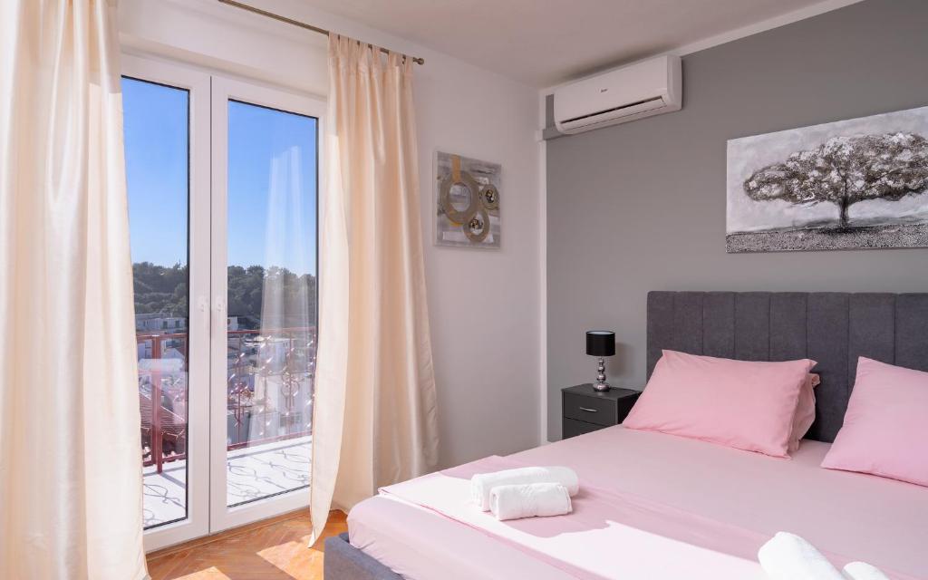 a bedroom with a bed with pink pillows and a window at Villa M&M - ZF Hvar in Hvar
