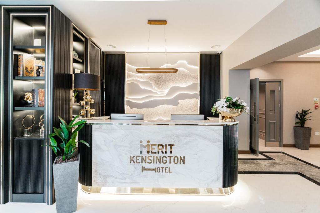 einen Wartebereich in einer Hotellobby mit einem Schild, das herzhaftes Hotel liest in der Unterkunft Merit Kensington Hotel in London