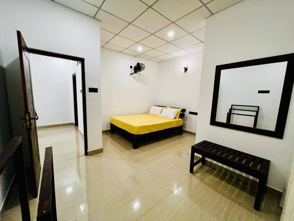 a bedroom with a yellow bed and a mirror at Theon Resort in Anuradhapura