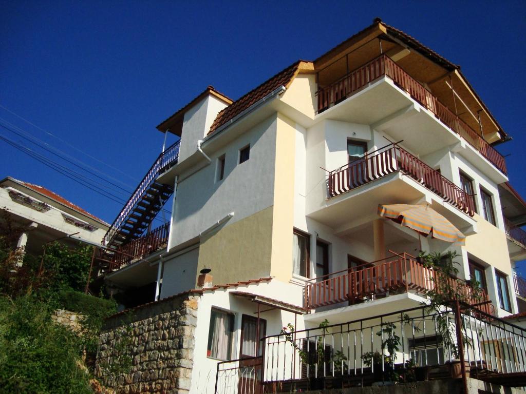 a white building with red balconies and an umbrella at Sonce Guest House in Ohrid