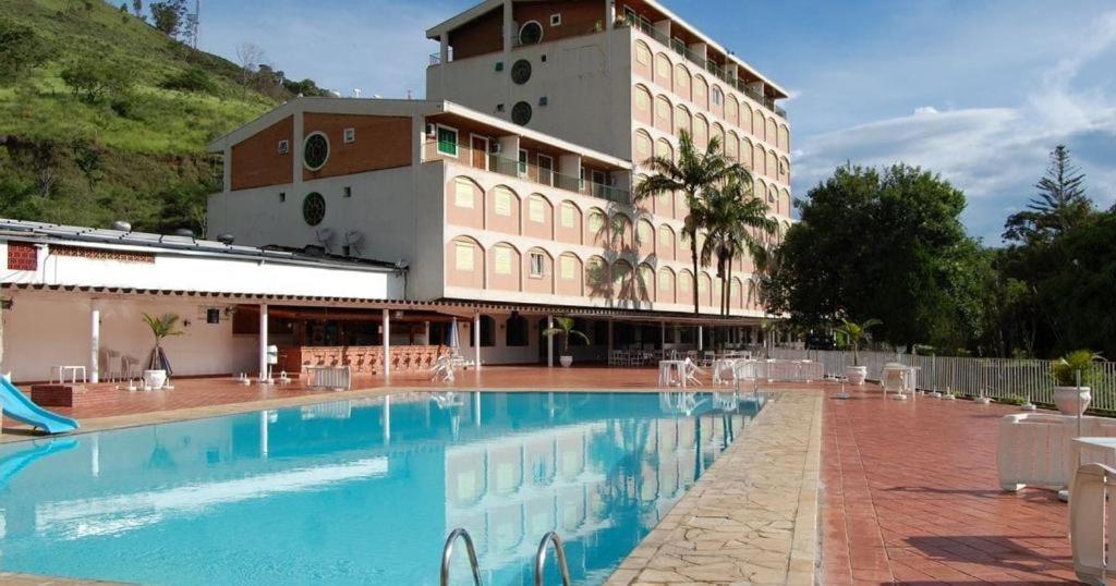 a hotel with a swimming pool in front of a building at HOTEL CAVALINHO BRANCO in Águas de Lindóia