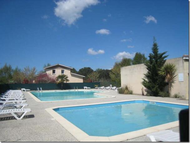 uma piscina com cadeiras brancas em Villa dans résidence privée au bord du lac d'Hourtin port em Hourtin
