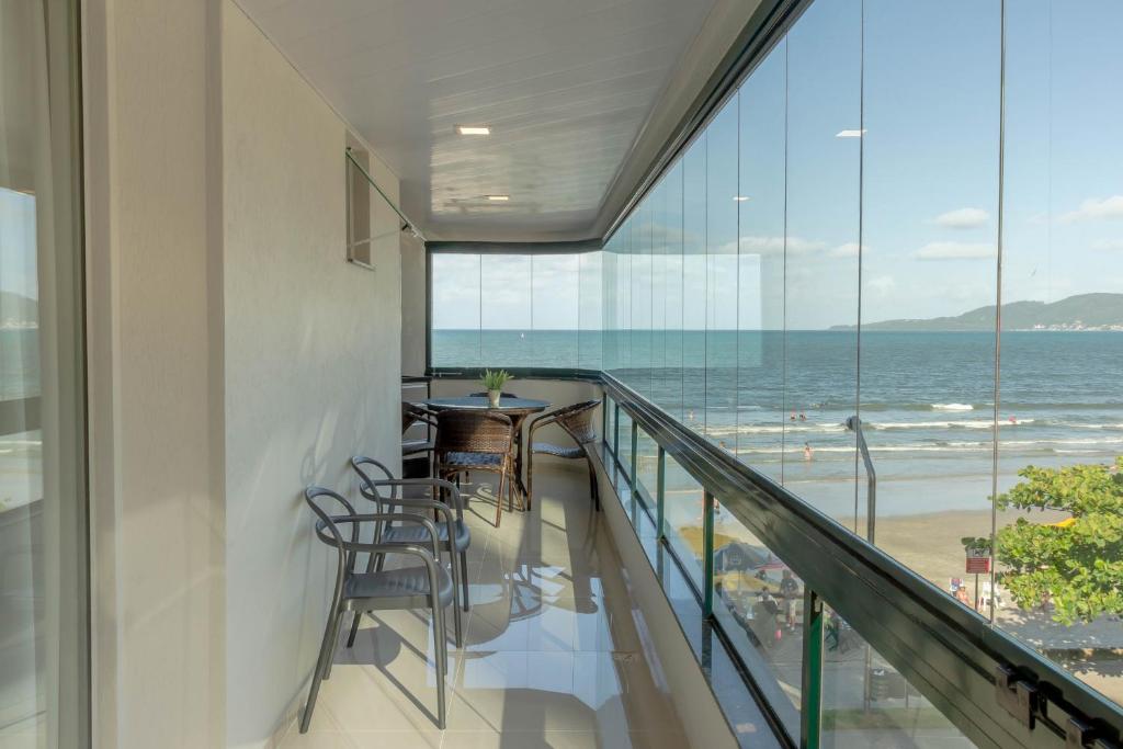 uma varanda com cadeiras e vista para o oceano em Apartamento em condomínio Pé na Areia em Itapema N1672 em Itapema