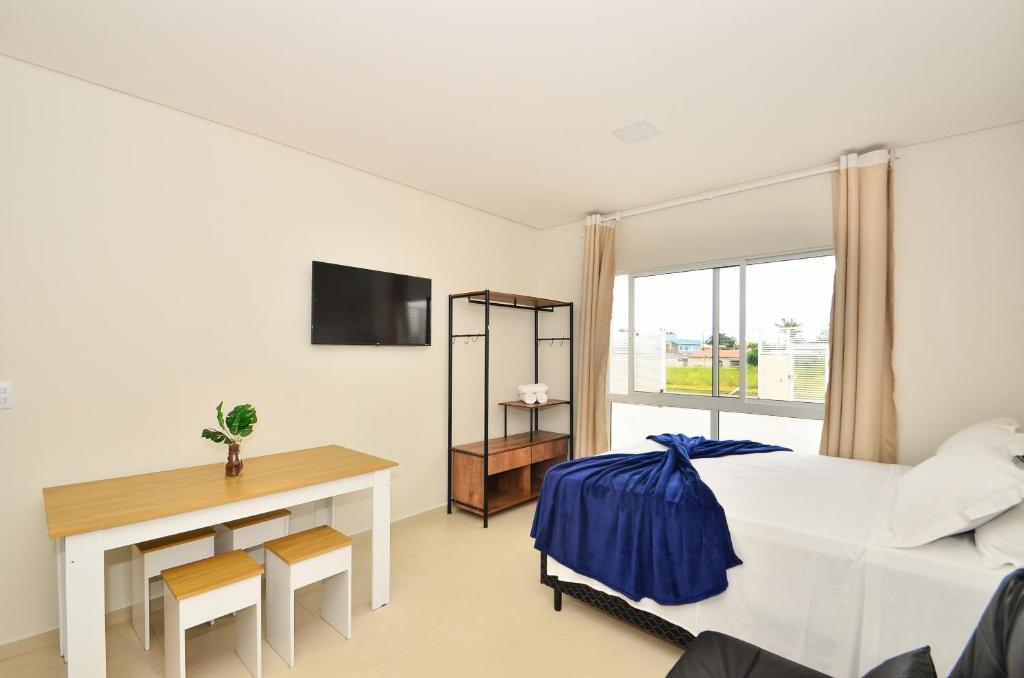 um quarto com uma cama, uma secretária e uma janela em InHome - Estúdio 02, conforto e aconchego no Campeche N1518 em Florianópolis