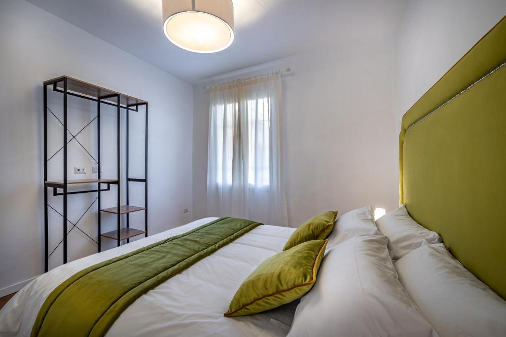 una camera da letto con un grande letto bianco con cuscini verdi di JCL first apt in the hearth of Florence a Firenze