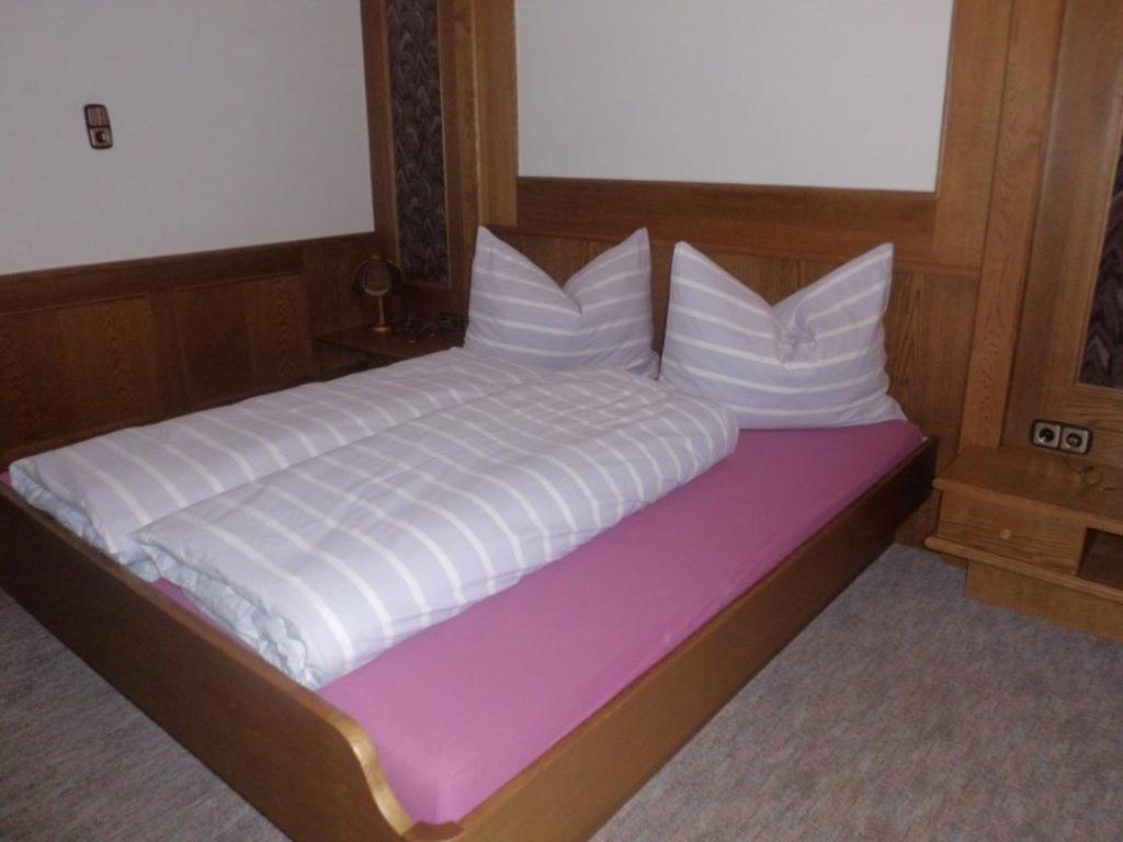 uma cama com lençóis brancos e almofadas em Ferienwohnung Reinstadler Ilse em Jerzens