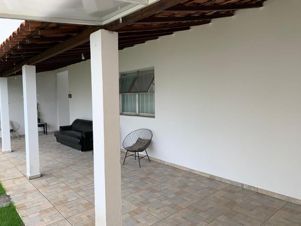 eine Terrasse mit einem schwarzen Sofa und einem Stuhl in der Unterkunft Casa de hospedagem providências in Cachoeira Paulista