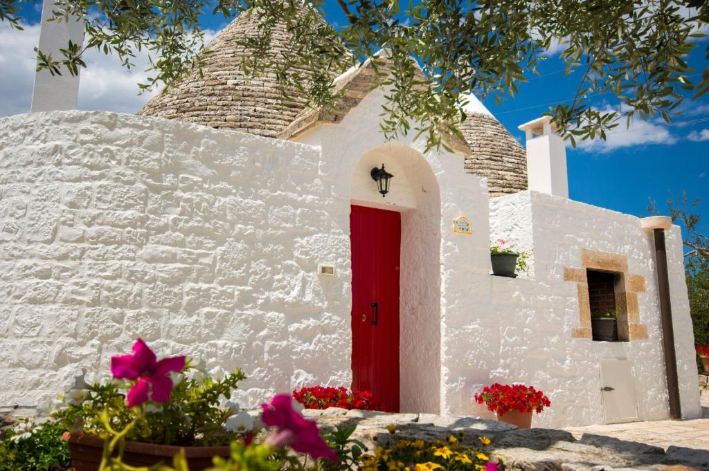a white building with a red door and flowers at I Trulli degli Ulivi in Locorotondo