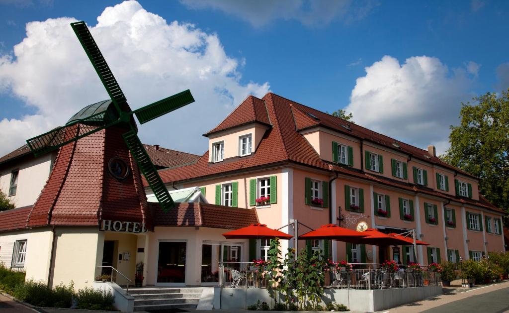 un gran edificio con un molino de viento delante de él en Hotel Restaurant zur Windmühle, en Ansbach