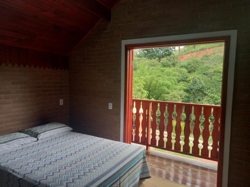 a bedroom with a bed and a large window at Recanto Três Irmãs, chalé 2 in Camanducaia