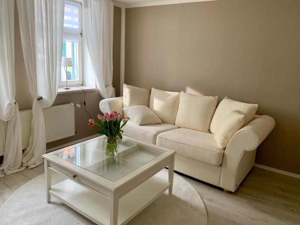 a living room with a white couch and a glass table at Ferienhaus LiebensWert an der St Stephan Kirche Tangermünde in Tangermünde