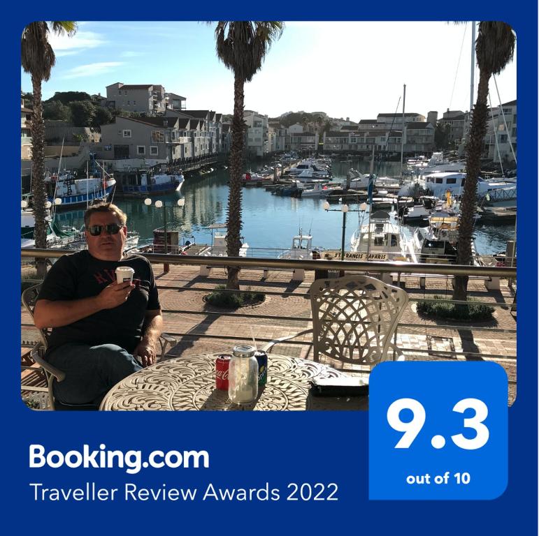 a man sitting at a table taking a picture of a marina at Ships Bell at Port St Francis in St Francis Bay