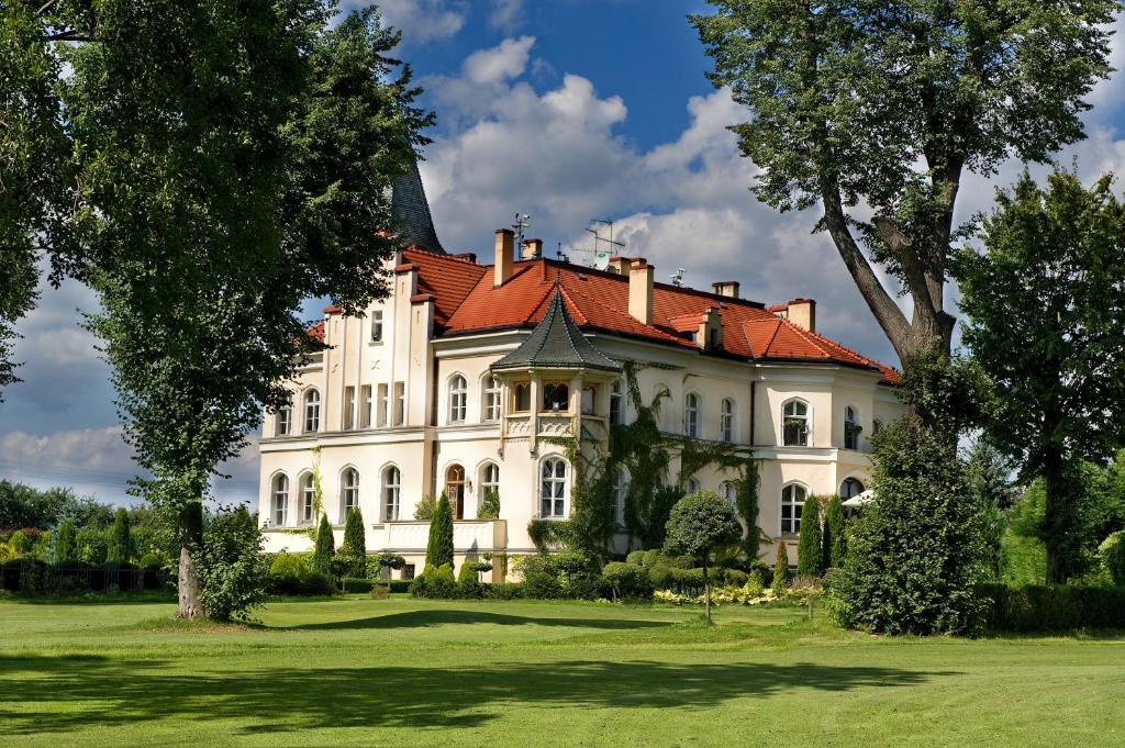 una gran casa blanca con techo rojo en Pałac Brzeźno Spa & Golf, en Oborniki Śląskie