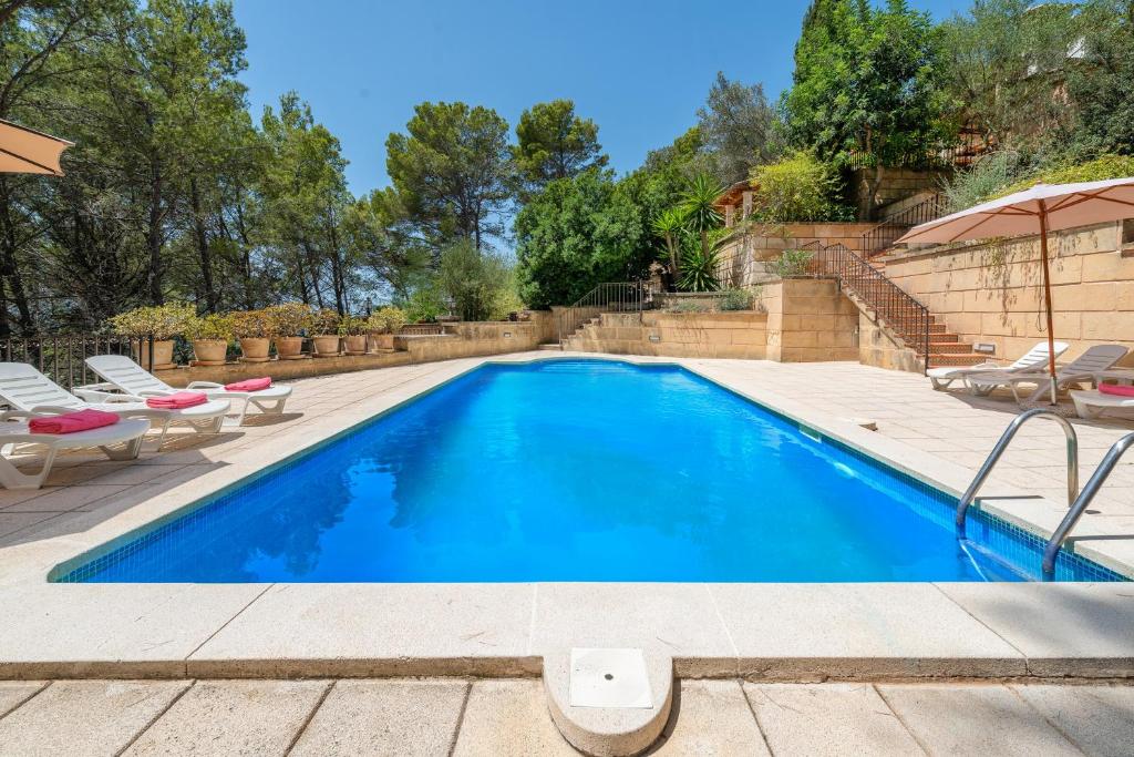 una piscina con sillas y sombrilla en NEW! Villa CAN PERE for 10 people with pool and panoramic views, en Es Capdellà