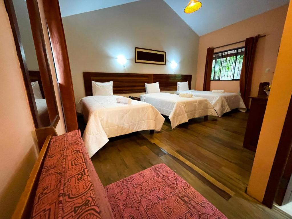 a hotel room with two beds and a red rug at Manish Hotel Ecólogico in Pucallpa