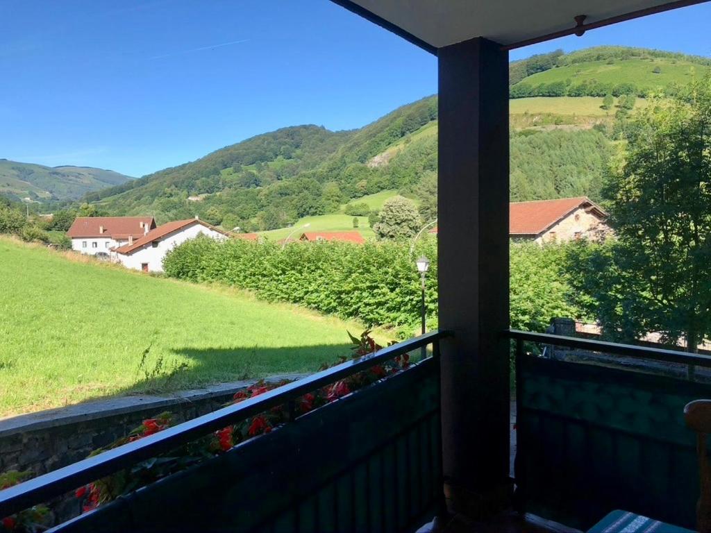 een balkon met uitzicht op een groen veld en de bergen bij Apartamento Rural Areso - Fraxkuenea in Areso