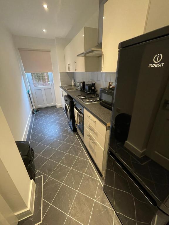 a kitchen with a black refrigerator and a tile floor at Hosted By Ryan - 2 Bedroom House in Liverpool