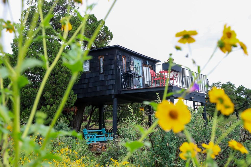 a tree house with a deck and flowers at Ashley's Treehouse at El Mistico in Nogal