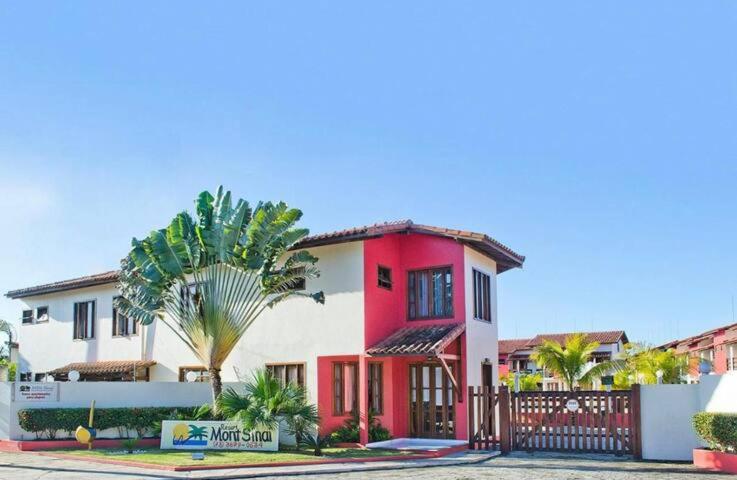 a red and white house with a palm tree at Residencial Mont Sinai Tonziro -Taperapuan in Porto Seguro