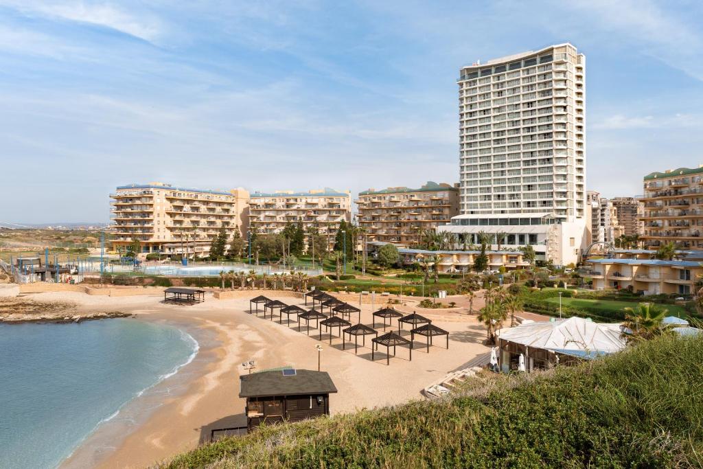 een strand met een groep tafels en stoelen bij Resort Hadera by Jacob Hotels in H̱adera