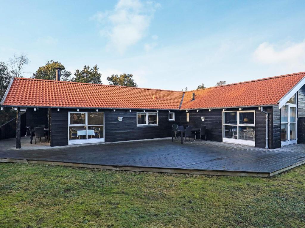 une maison noire avec un toit orange et une terrasse dans l'établissement 8 person holiday home in Hals, à Hals