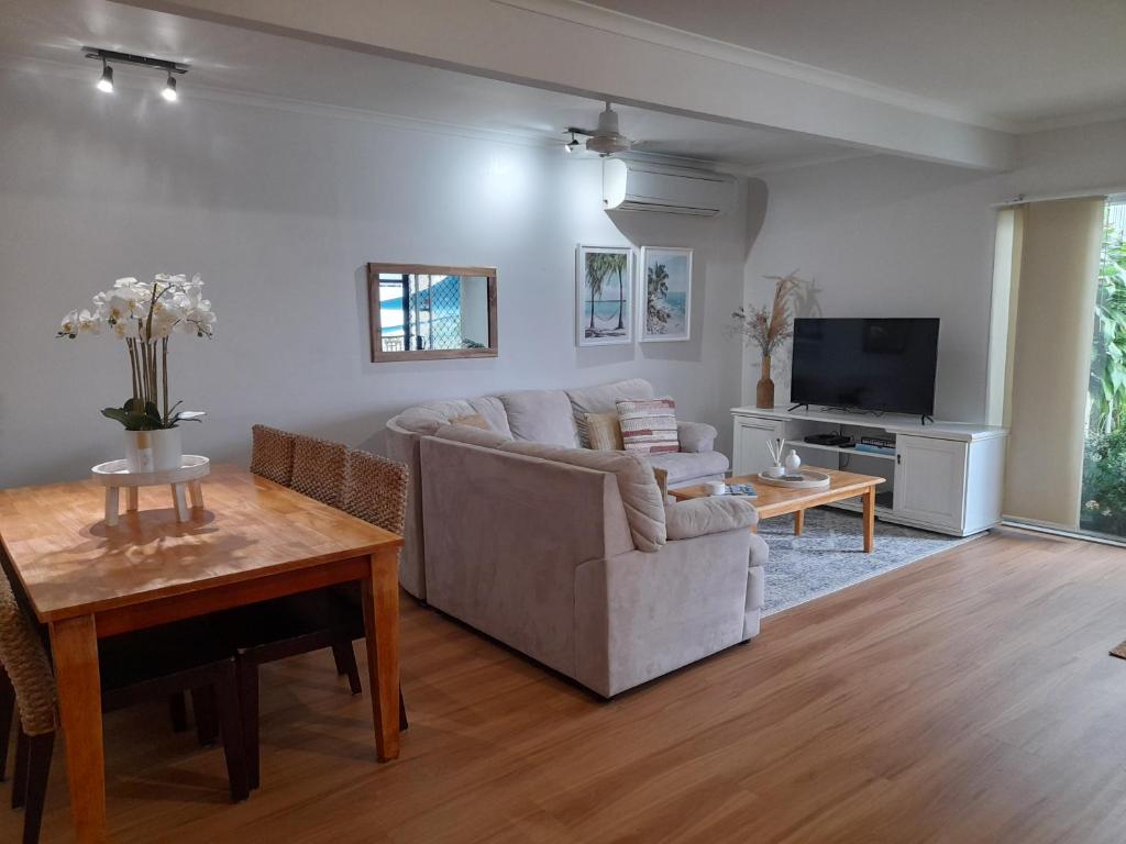 a living room with a couch and a tv at Airlie Apartments in Airlie Beach
