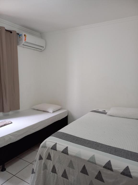 2 camas en una habitación con paredes blancas en Recanto Sete Mares Hospedagem Familiar, en Balneário Camboriú