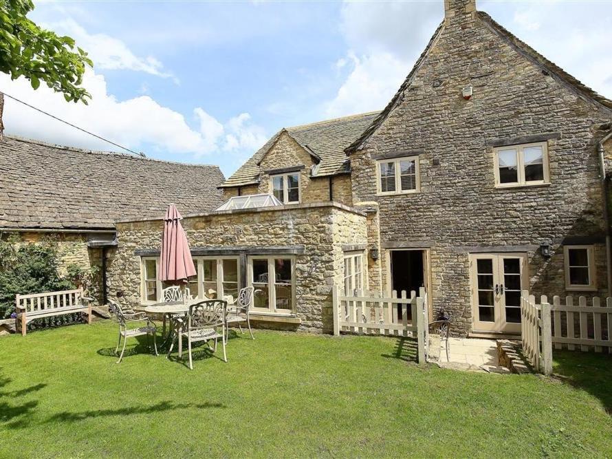 a stone house with a table and chairs in the yard at Coach House Burford in Burford
