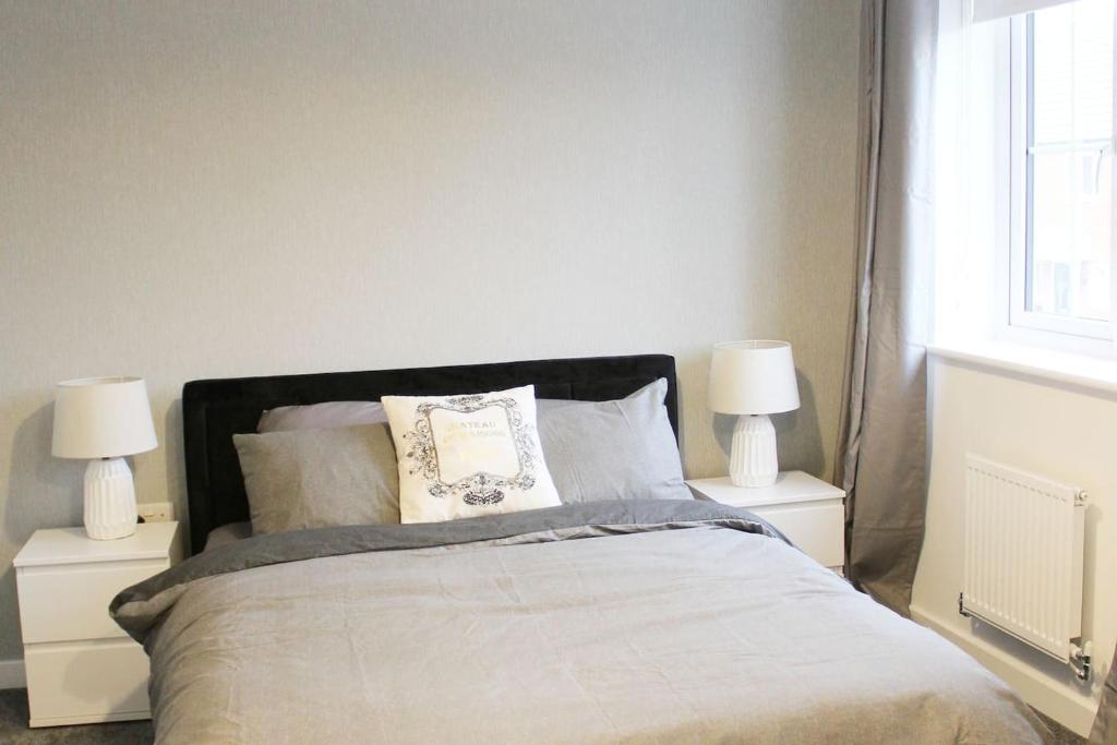 um quarto com uma cama com duas mesas de cabeceira brancas em Penelope Maison - London in 50 Mins, Free Parking, 1 BDRM Home em Peterborough