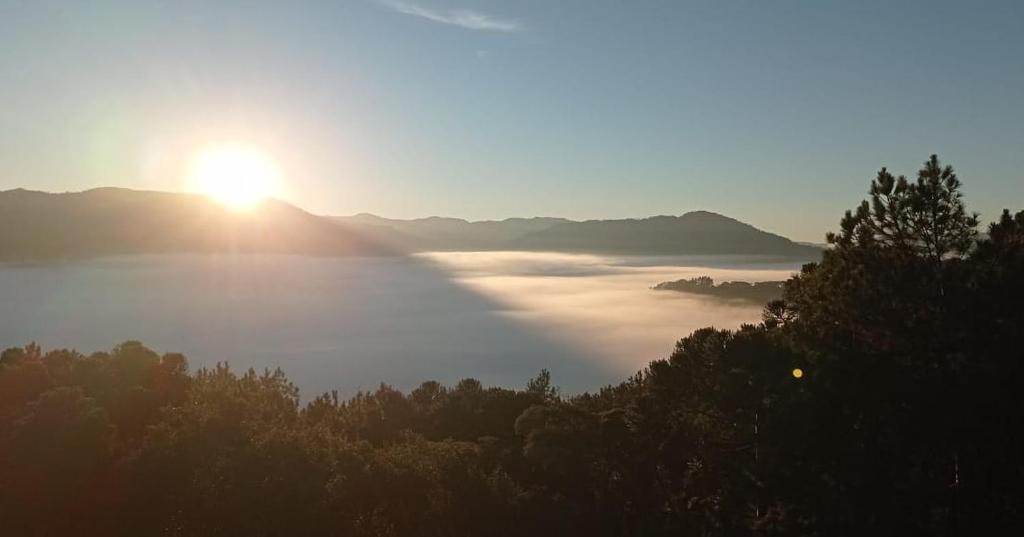 a view of the sun rising over a fog covered valley at Pousada Colina do Sol in Urubici