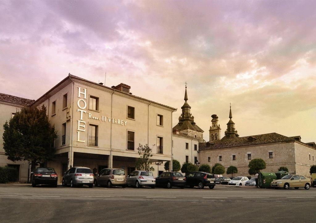 a building with cars parked in a parking lot at Hotel II Virrey in El Burgo de Osma